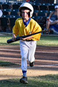 Bat boy Jack Myhrvold running back to the dugout from home plate with a bat in-hand.